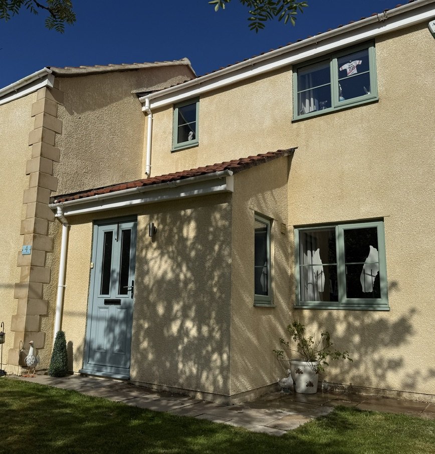 Cream rendered house with green windows after render cleaning