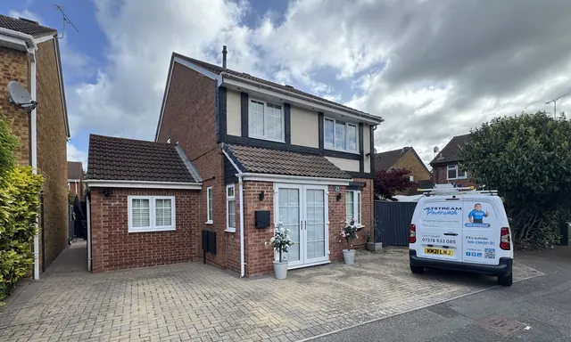 Family home with a dull, dirty tiled roof under cloudy skies before cleaning