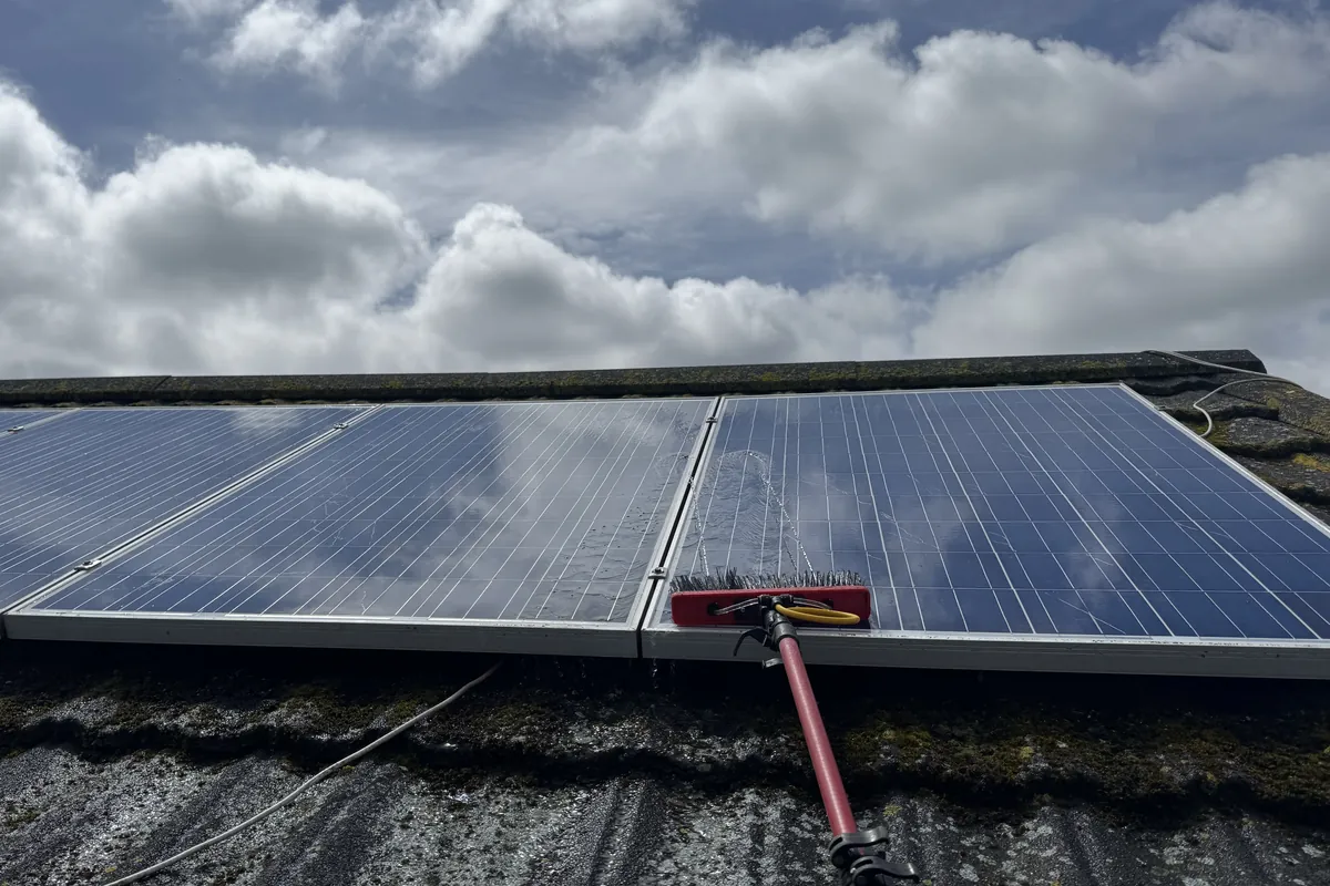 Solar panel cleaning using a water-fed soft brush on a residential roof