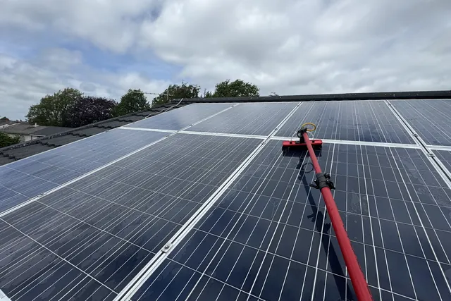 Solar panels being cleaned with a soft water-fed brush