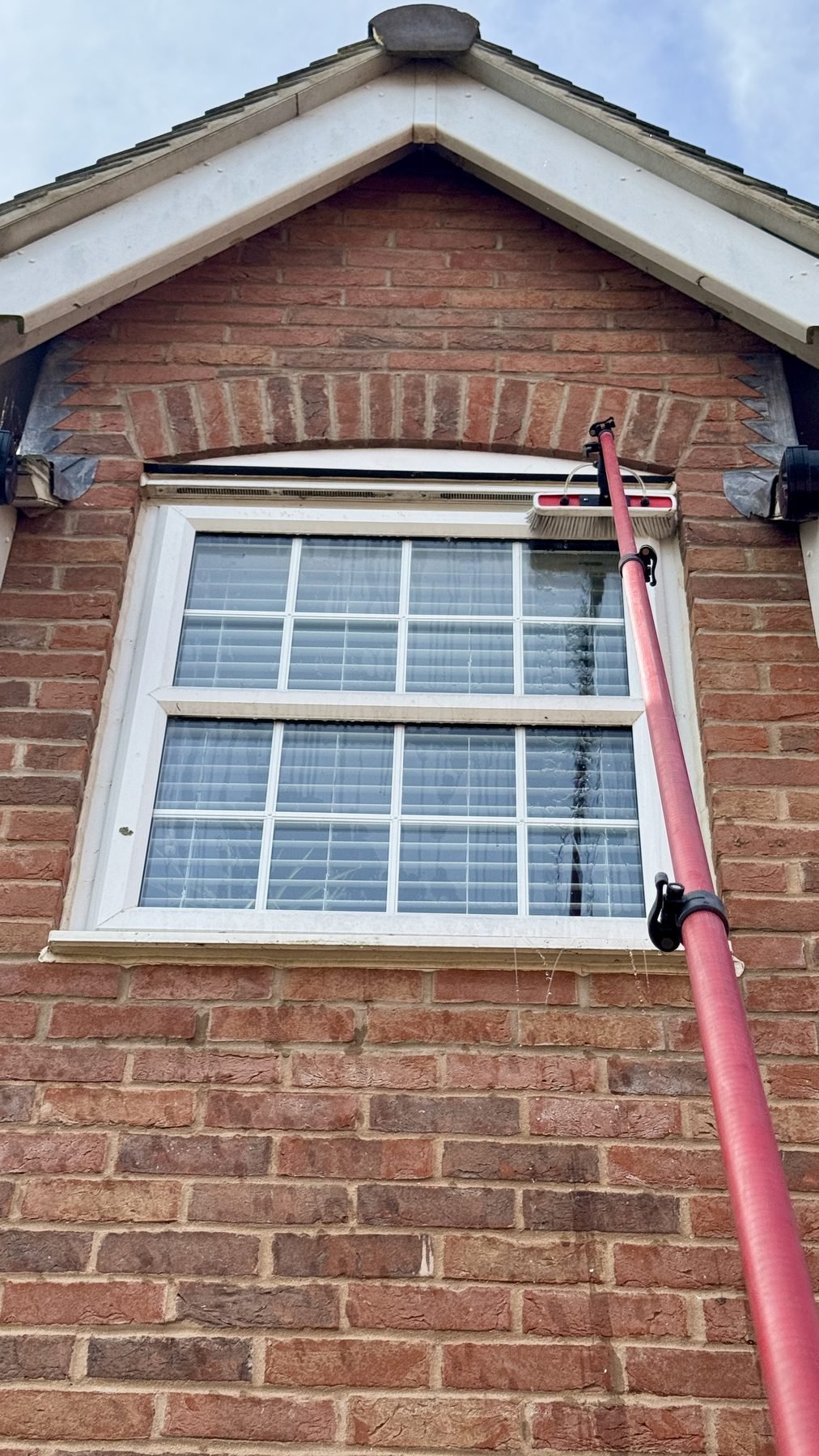 Cleaning a gable-end window with a pole