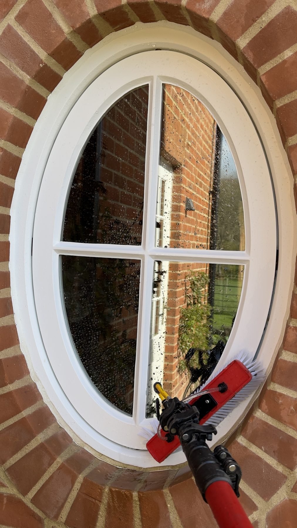Cleaning an oval window with a pole and brush