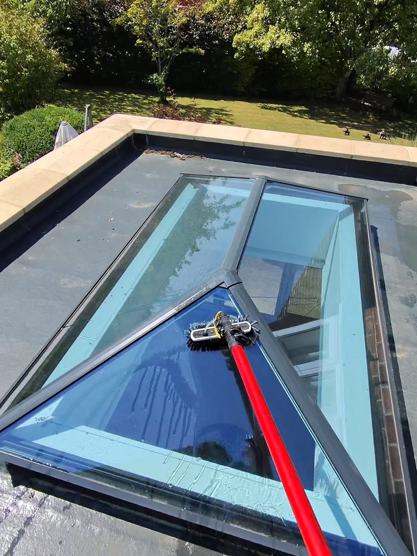 Cleaning a roof lantern with a pole and brush