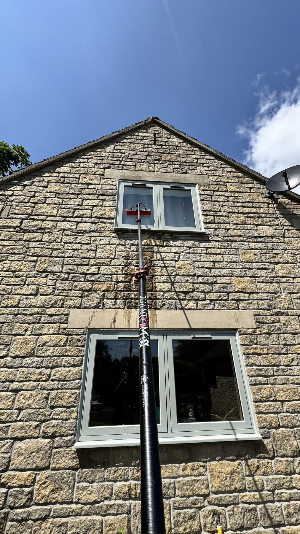 Reaching high windows on a stone house with a pole